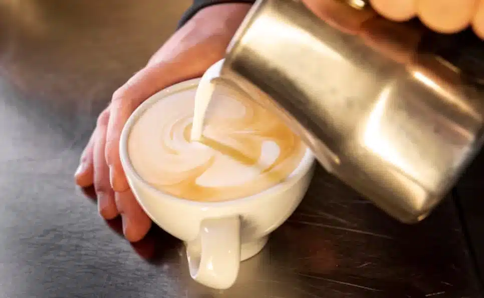 An innovative man prepares a cup of Starbucks coffee using soy milk, catering to diverse dietary preferences.