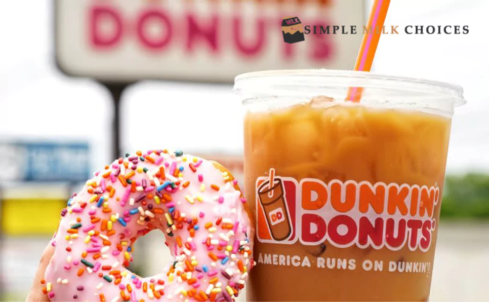 A close-up of a clear glass filled with Dunkin' coffee and a delectable donut resting beside it, a tempting treat for any coffee lover.
