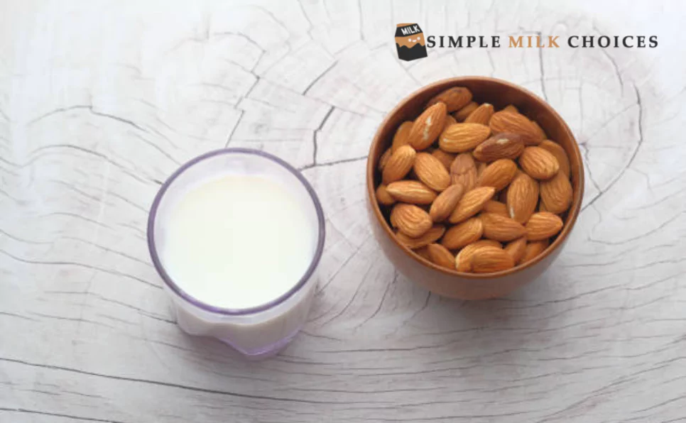 A glass filled with creamy almond milk sits beside a bowl overflowing with whole almonds, highlighting the connection between the beverage and its raw ingredient.