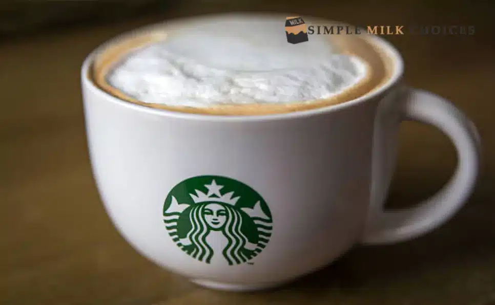 An aromatic cup of Starbucks coffee topped with creamy, coconut milk, served in a white ceramic mug on a wooden table.