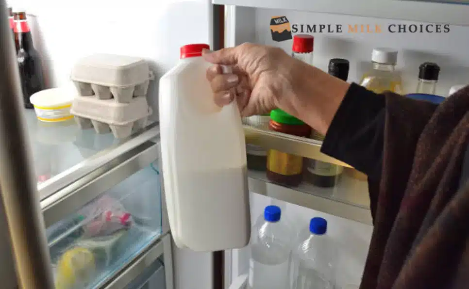 A woman placing a gallon of soy milk inside a freezer to thaw it for later use.