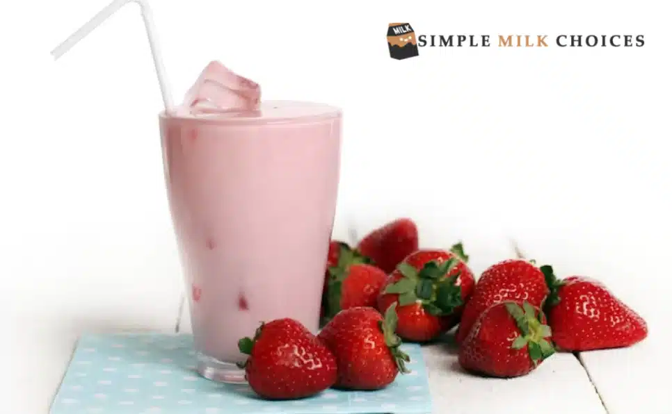 An overhead view of a clear glass filled with icy strawberry milk, garnished with fresh strawberries on the rim.