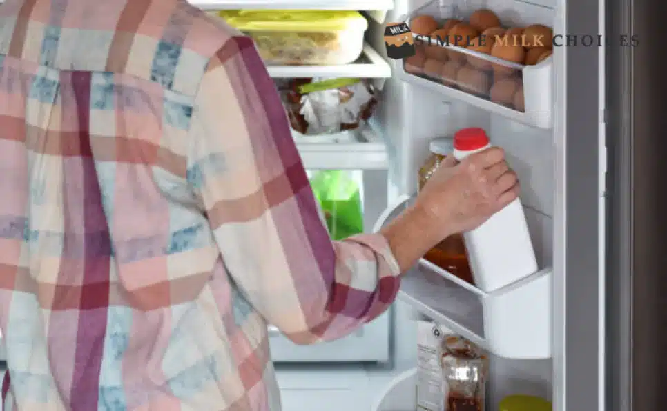 A man placing a bottle of soy milk into a freezer for storage to keep it fresh and ready for use.